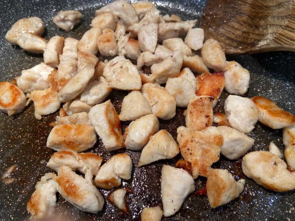 Cubed chicken is sauteed in a pan