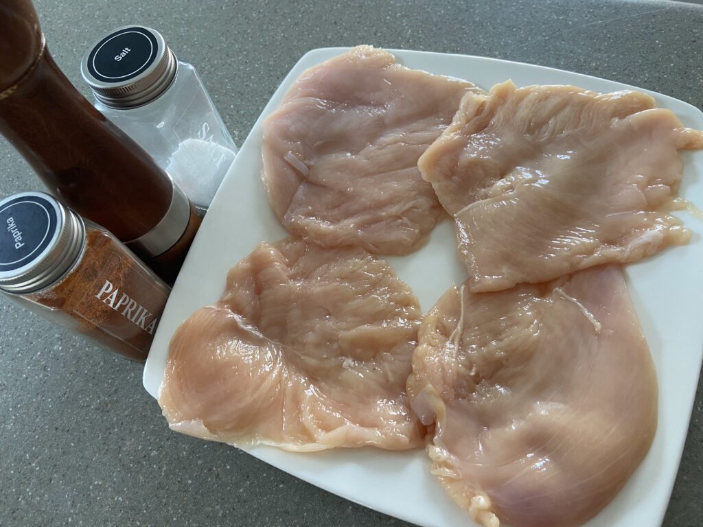 chicken cutlets arranged on a plate and seasoned with salt and pepper and paprika