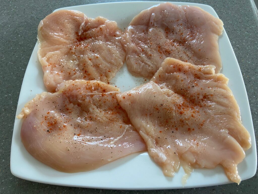 chicken cutlets arranged on a plate and seasoned with salt and pepper and paprika