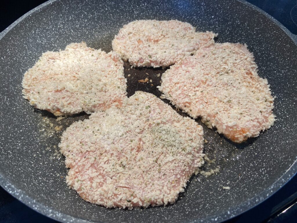 Chicken cutlets added to pan to cook