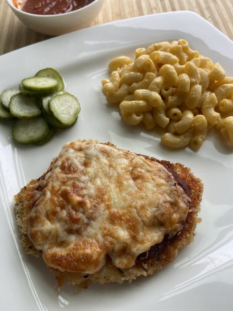 Chicken parmesan and mac and cheese served on a plate