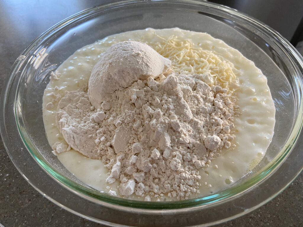 yogurt, cottage cheese, eggs, flour and shredded cheese are added to a bowl.