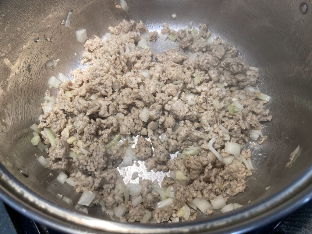 Ground chicken sausage sautéed in pot with chopped onions