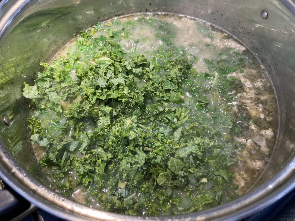 Kale added to pot of chicken sausage, kale and potatoes soup
