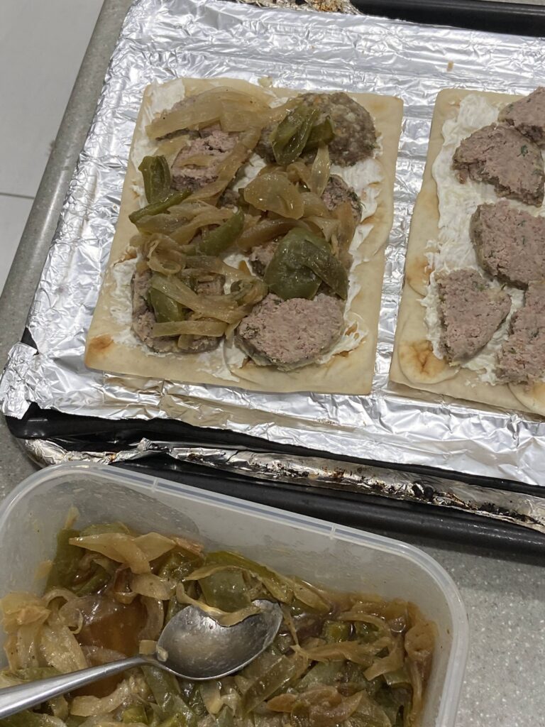Add the cut-up meatballs pieces on the flatbreads and add the sautéed peppers and onions 