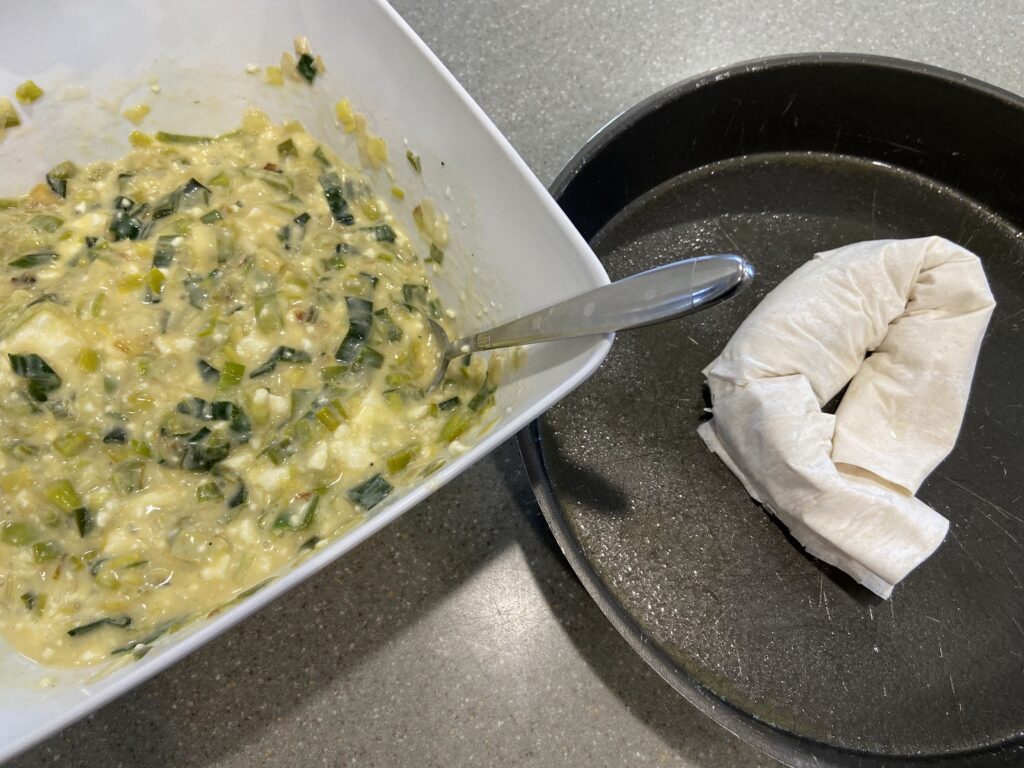 mixture of leeks, eggs, feta cheese, yogurt is spread evenly over phyllo (filo) pastry sheets