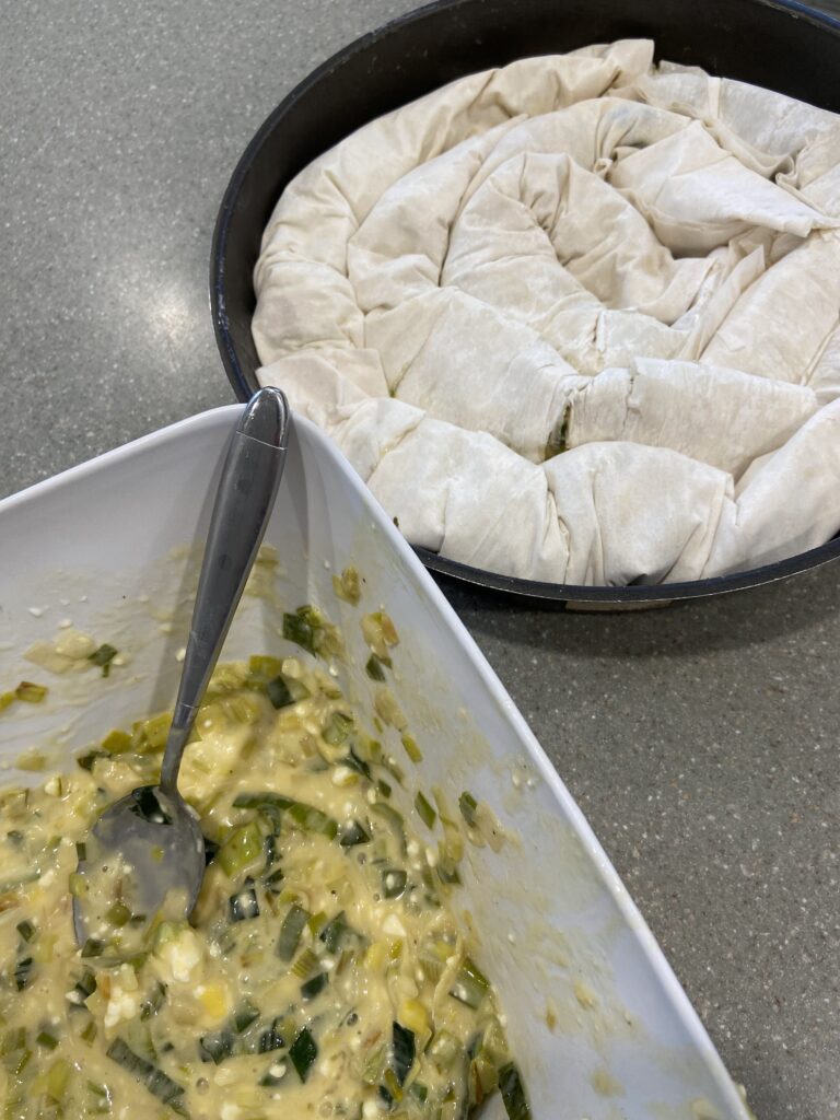 Filled phyllo (filo) dough sheets are arranged in a circle in the round baking pan