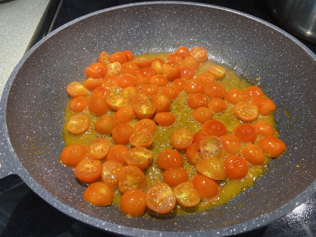 blistered cherry tomatoes in a pan with olive oil