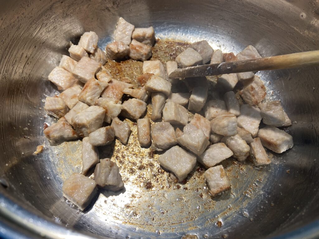 pork cubes added to a pot with olive oil and sauteed until golden brown on all sides