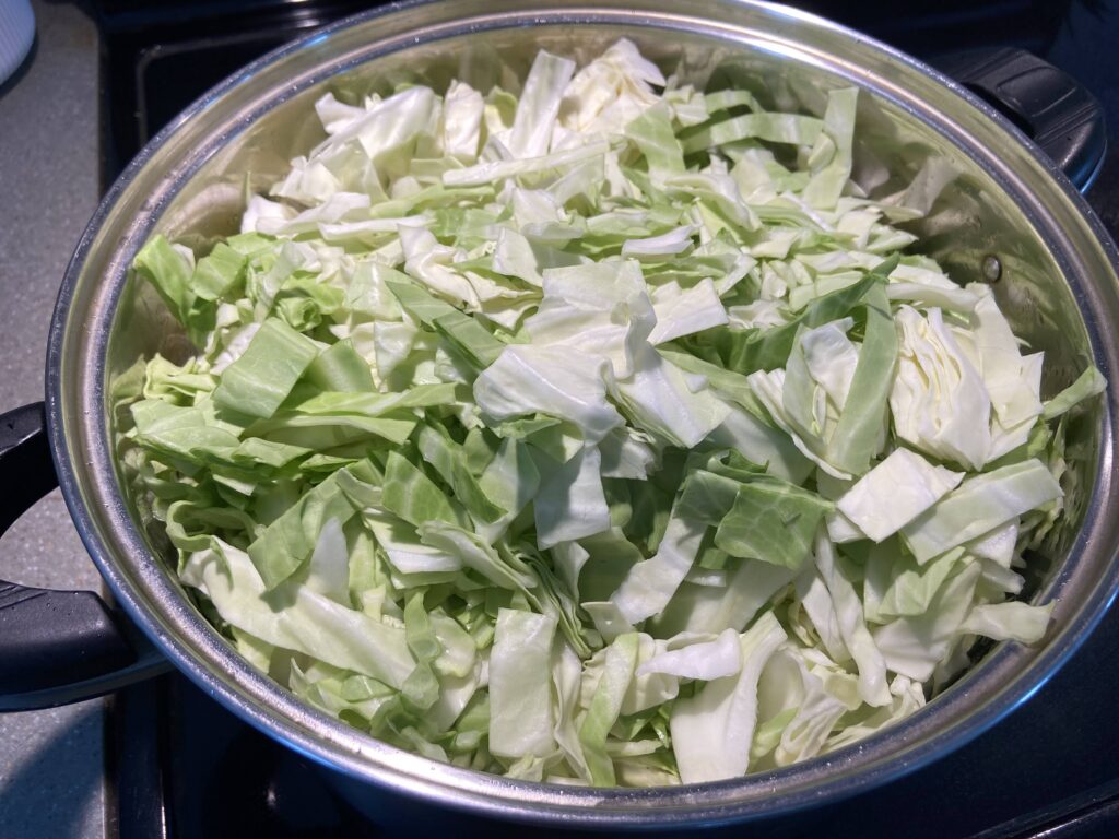 chopped cabbage cooked in a pot over browned pork cubes