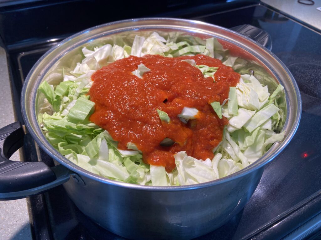 marinara sauce added on top of chopped cabbage in a Dutch oven
