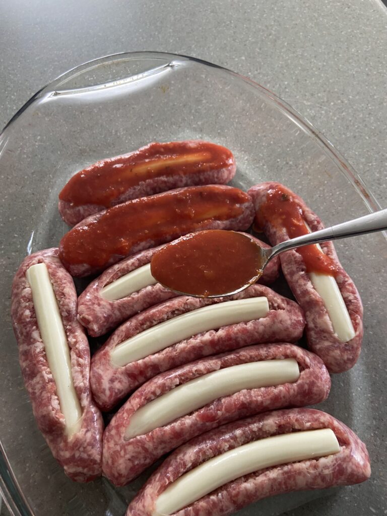 A plate with sausage and ketchup on it.