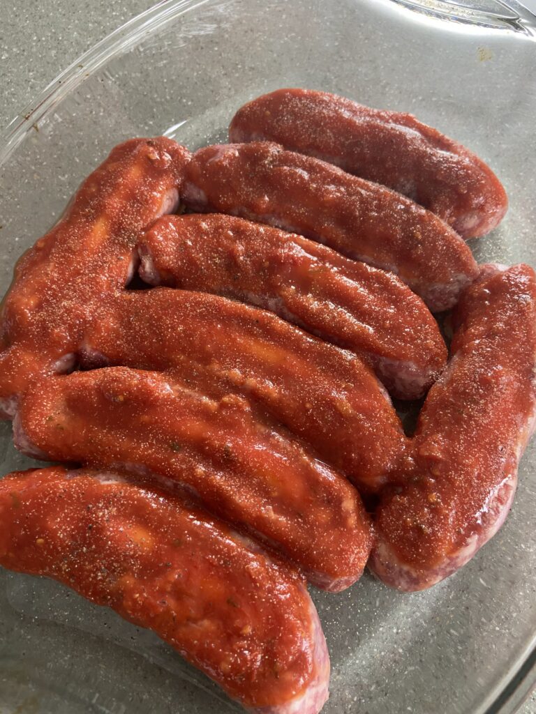 Six sausages in a glass dish on a counter.